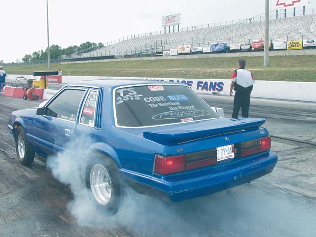 0211mmff_01zoom 1985_Ford_Mustang Rear_Drivers_Side_View_At_Track